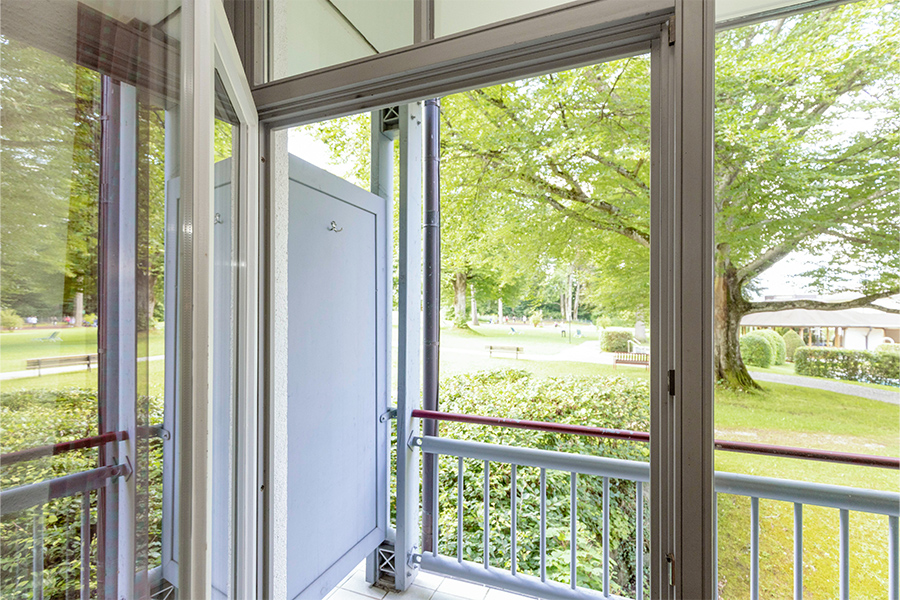 Aufnahme einer Balkontür mit dahinterliegendem Balkon und Blick in den Garten.