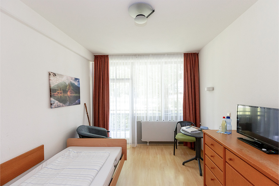 Innenaufnahme eines Patientenzimmers mit Bett, Kommode, Tisch und Fernseher. Innenaufnahme eines Patientenzimmers mit Bett, Kommode, Tisch und Fernseher.