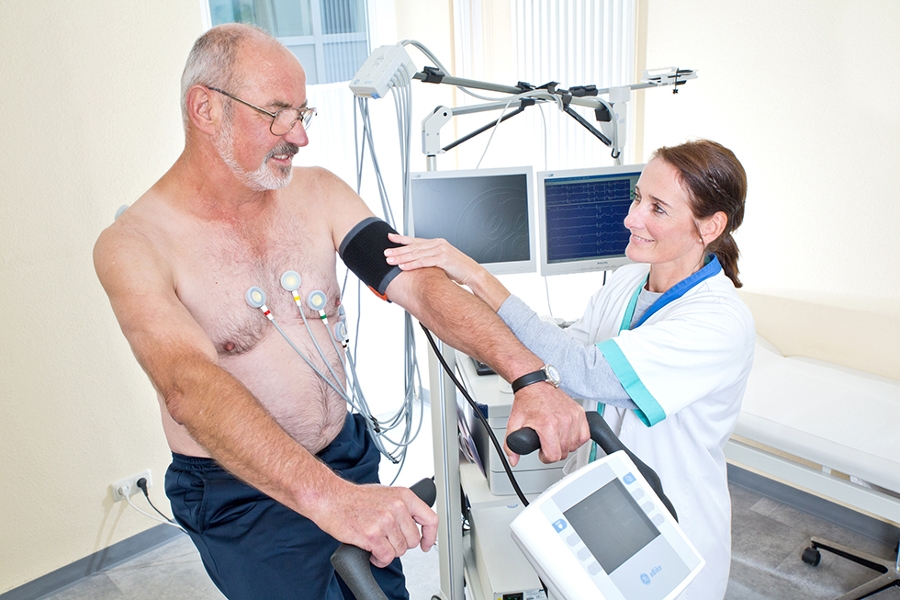 Eine Therapeutin macht ein Belastungs-EKG bei einem älteren Patienten. Eine Therapeutin macht ein Belastungs-EKG bei einem älteren Patienten.