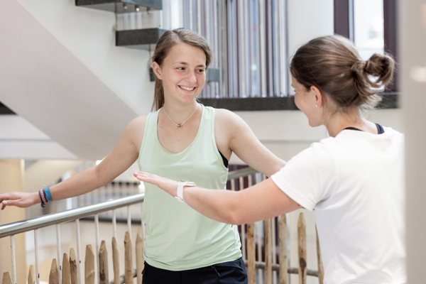 Eine Physiotherapeutin zeigt einer jungen Patientin im Treppenhaus Gleichgewichtsübungen Eine Physiotherapeutin zeigt einer jungen Patientin im Treppenhaus Gleichgewichtsübungen